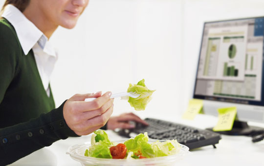 Eating a healthy salad at her work desk.